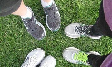 Close up photo of three people's running shoes