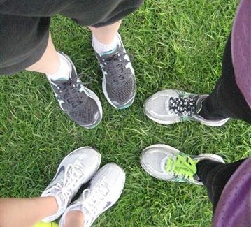 Close up photo of three people's running shoes