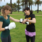 Personal Trainer is putting gloves on a female client outdoors