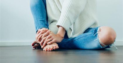 Photo of woman sitting on floor, clutching her ankle